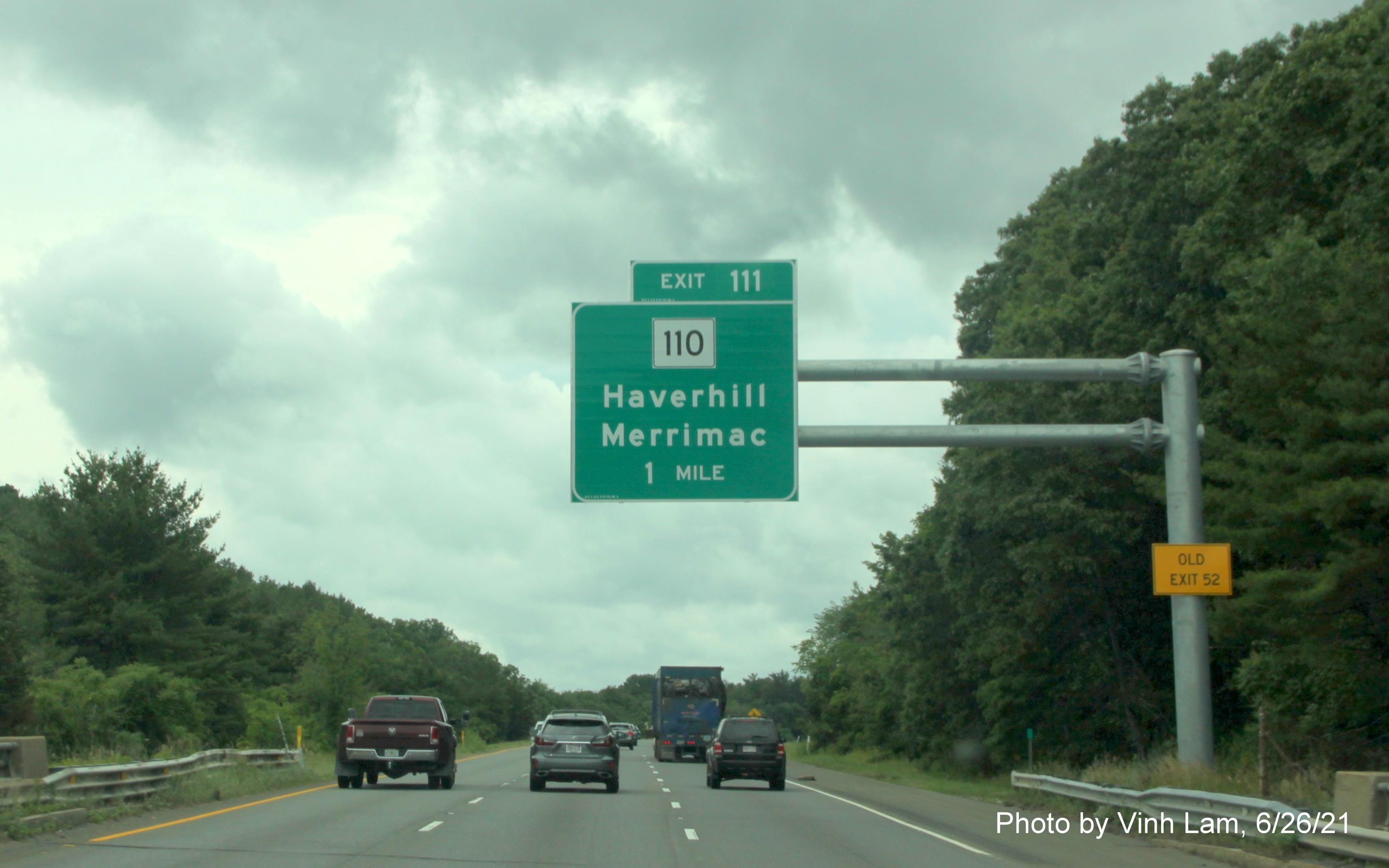 Image of 1 mile advance overhead sign for MA 110 exit with new milepost based exit number and yellow Old Exit 52 advisory sign on support on I-495 South in Haverhill, photo by Vinh Lam, June 2021