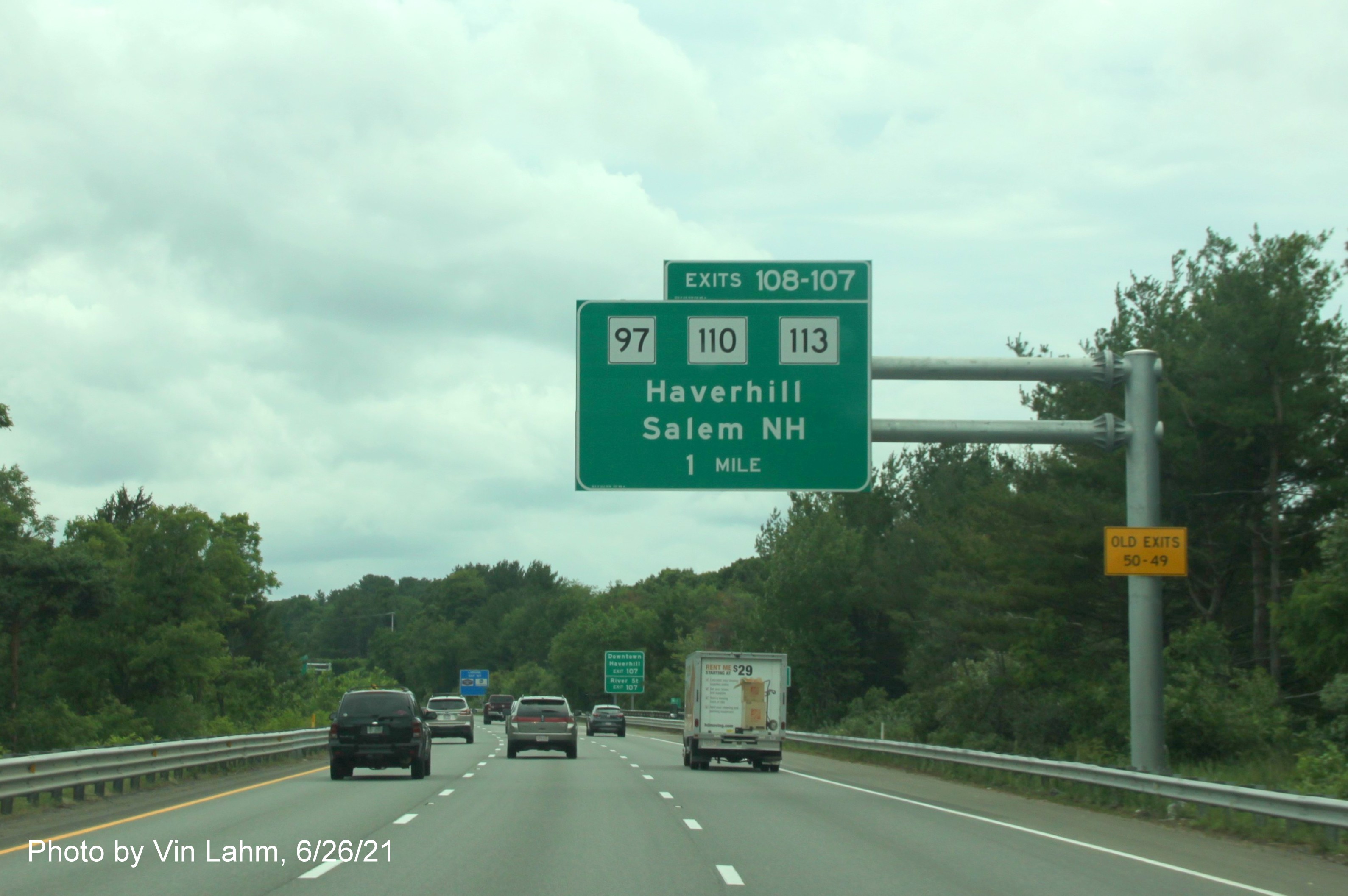 Image of 1 Mile advance overhead sign for MA 97 and MA 110/113 exits with new milepost based exit numbers and yellow Old Exits 50-49 advisory sign on support on I-495 South in Haverhill, photo by Vinh Lam, June 2021