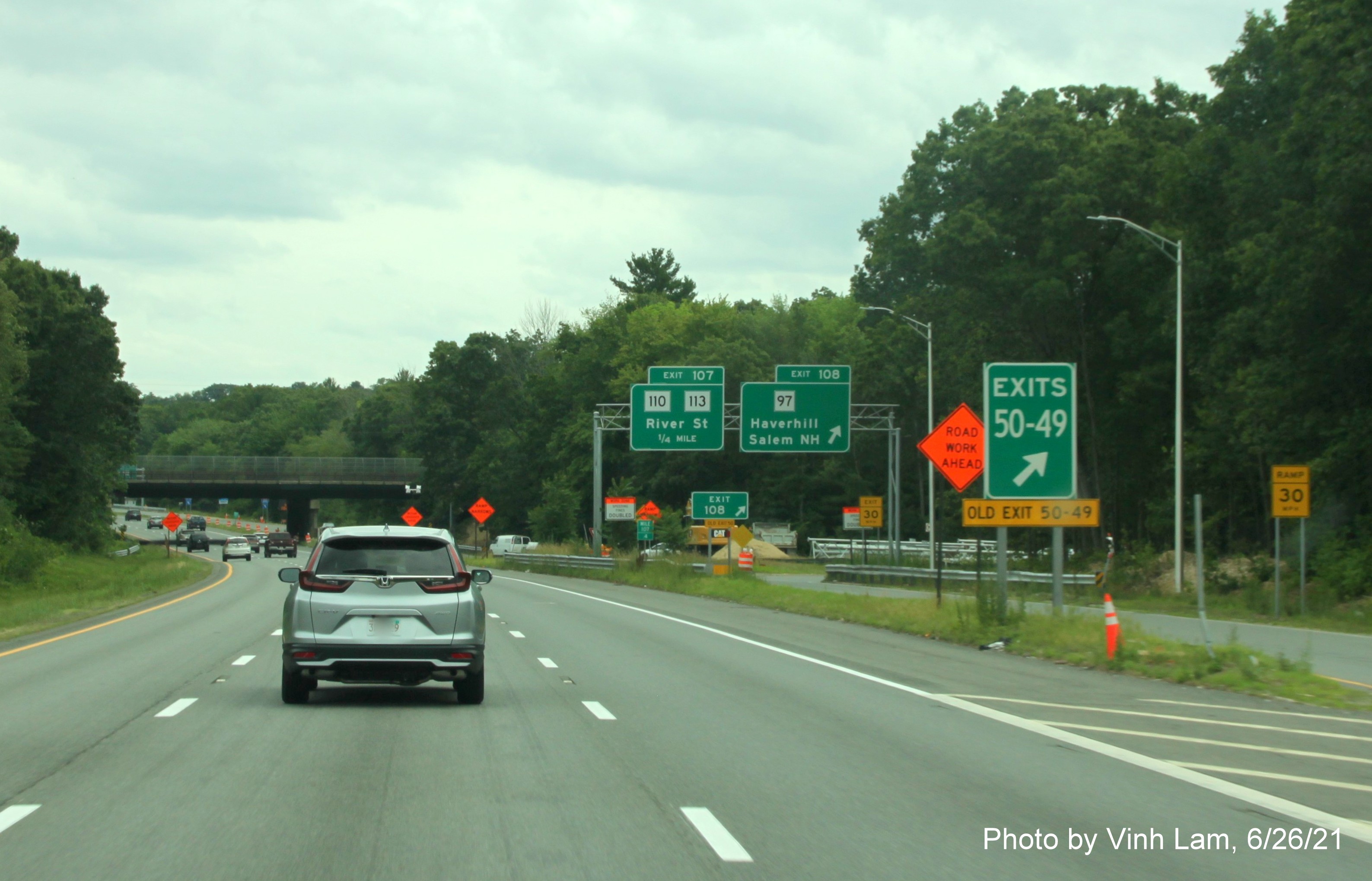 Image of gore sign at start of C/D lanes for MA 97 and MA 110/113 exits with unchanged sequential exit numbers and yellow Old Exit 50-49 sign below as seen from I-495 South in Haverhill, photo by Vinh Lam, June 2021