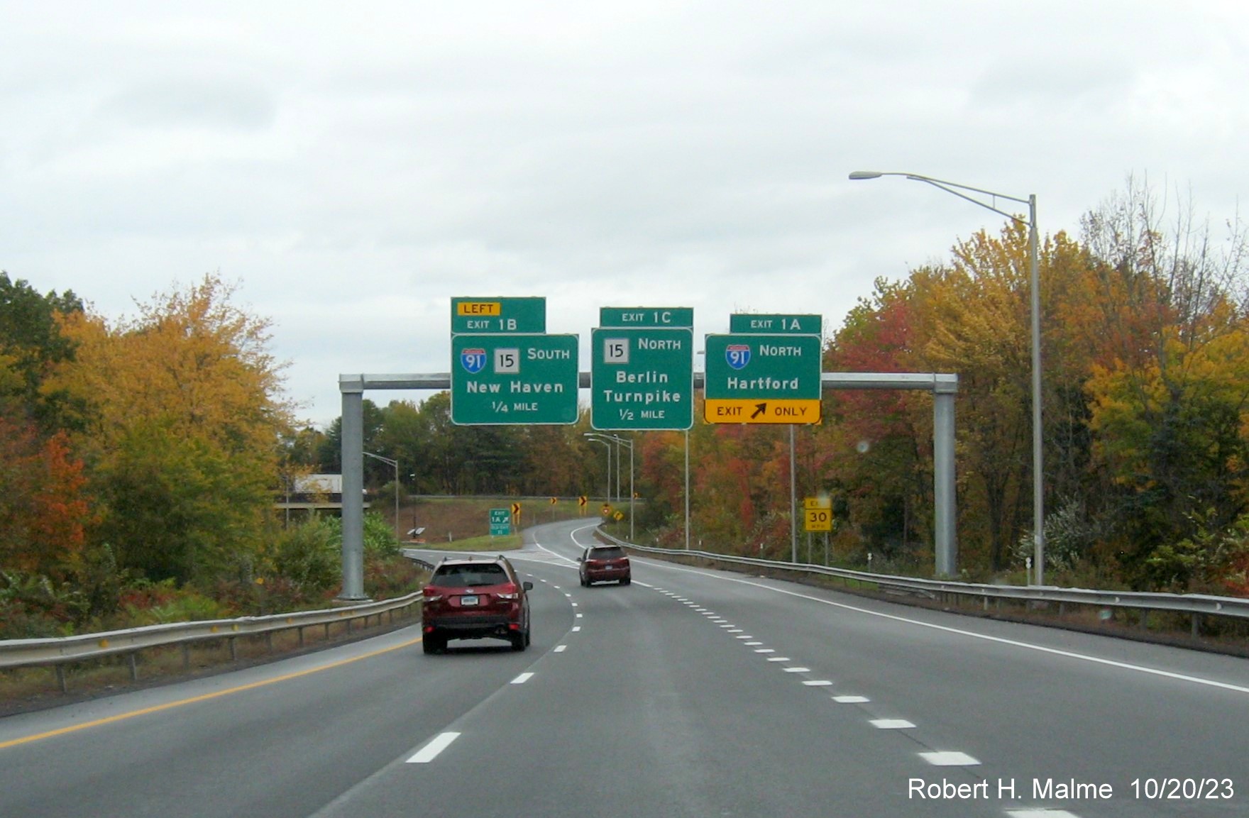 Image of new overhead signs with new milepost based exit number for the I-91/CT 15 exits at the 
        beginning of I-691 West in Meriden, October 2023