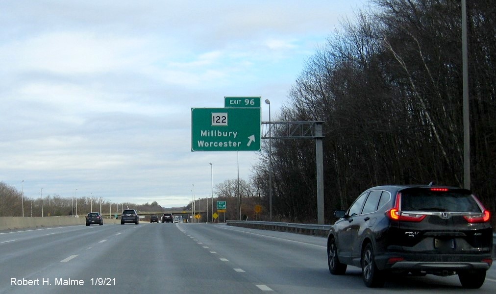 Image of overhead ramp sign for MA 122 exit with new milepost based exit number and gore sign with new number and yellow Old Exit 11 sign below on I-90/Mass Pike East in Millbury, January 2021