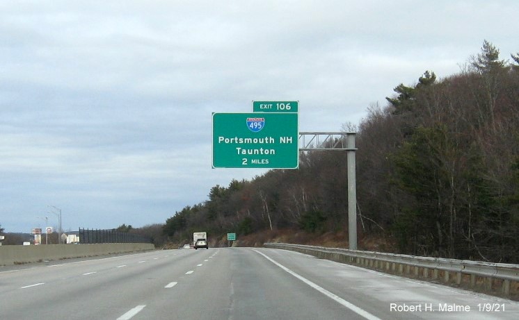 Image of 1-mile advance overhead sign for I-495 exit with new milepost based exit number and yellow old exit number sign on support post on I-90/Mass Pike East in Westboro, January 2021