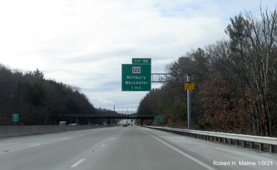 Image of 1-mile advance overhead sign for MA 122 exit with new milepost based exit number and yellow Old Exit 11 sign on support post on I-90/Mass Pike West in Millbury, January 2021