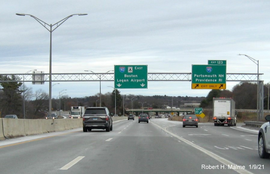 Image of overhead ramp sign for I-95 exit with new milepost based exit number and gore sign with new number in distance on I-90/Mass Pike East in Weston, January 2021