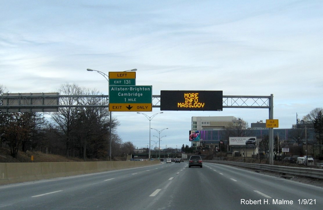 Image of 1-Mile advance overhead sign for Allston-Brighton-Cambridge exit with new milepost based exit number and yellow old exit number sign on right support post on I-90 East in Boston, January 2021