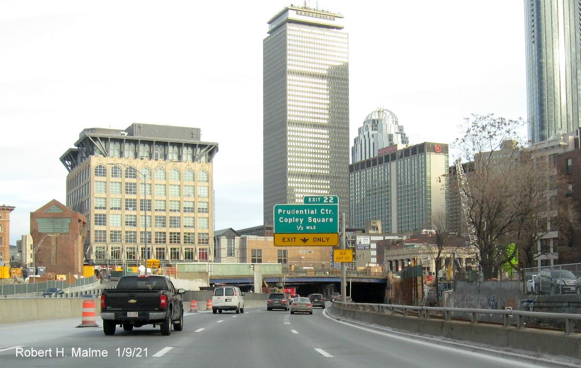 Image of 1/2 Mile advance overhead sign for Prudential Center exit with unchanged sequential exit number but yellow
                                      old exit sign on support post on I-90 East in Boston, January 2021