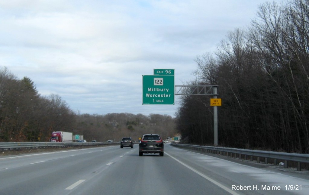 Image of 1-mile advance overhead sign for MA 122 exit with new milepost based exit number and yellow Old Exit 11 sign on support post on I-90/Mass Pike East in Millbury, January 2021