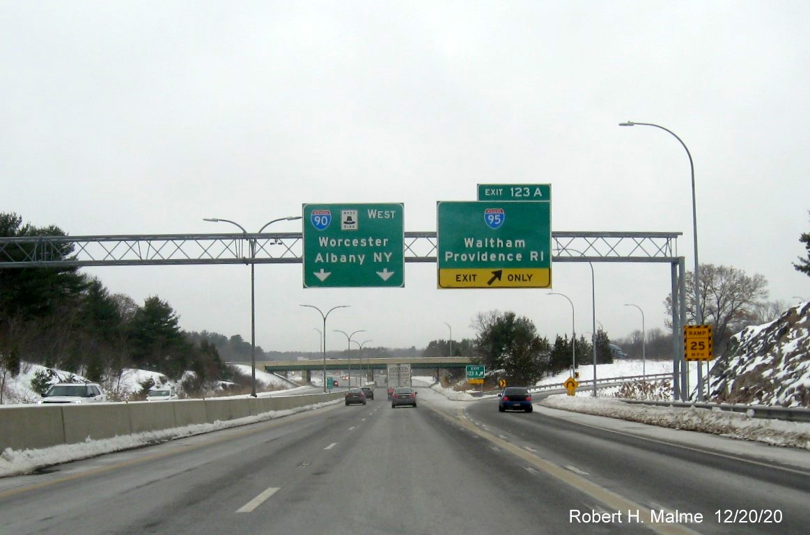 Image of overhead signs at ramp for I-95 exit with new milepost based exit number and gore sign beyond with new number and yellow old exit number tab below on I-90/Mass Pike West in Weston, December 2020