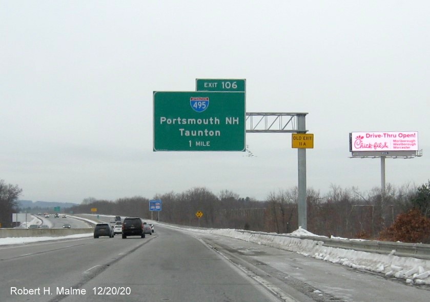 Image of 1-mile advance overhead sign for I-495 exit with new milepost based exit number and yellow old exit number sign on support post on I-90/Mass Pike West in Southboro, December 2020