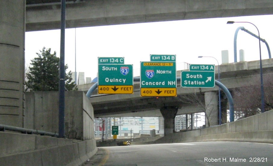 Image of overhead ramp signs for I-93 and South Boston exits with new milepost based exit numbers on I-90 
                                         East in Boston, February 2021