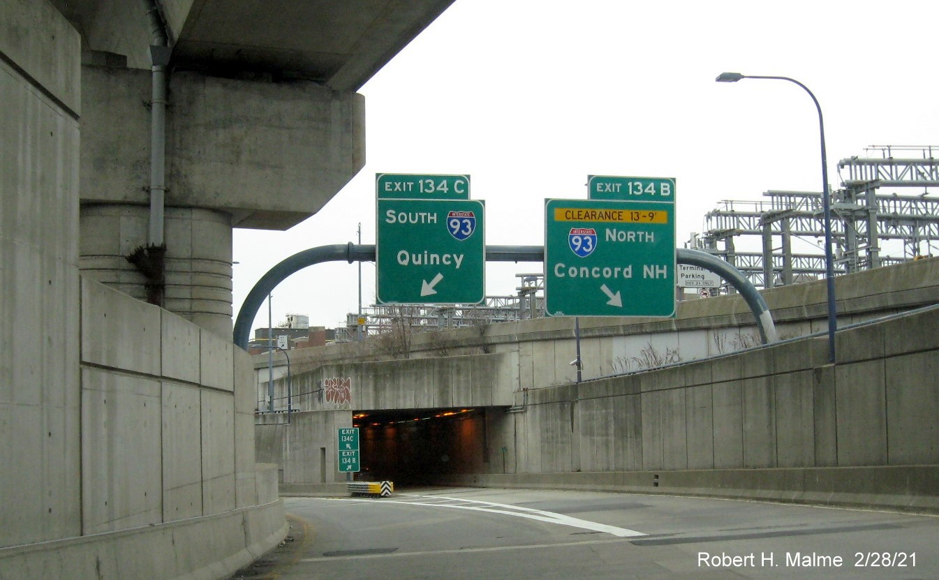 Image of overhead ramp signs for I-93 exits with new milepost based exit numbers on I-90 
                                         East in Boston, February 2021