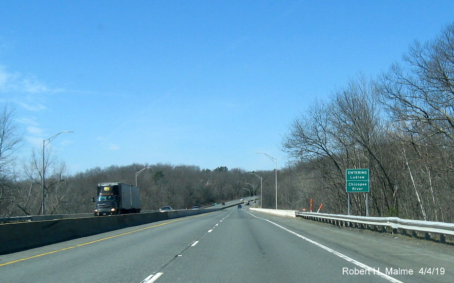 Image of combination town line/river crossing sign on I-90/Mass Pike West entering Ludlow at the Chicopee River
