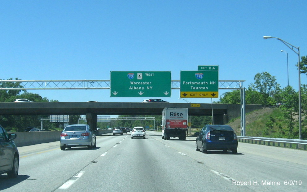 Image of newly placed overhead signs at ramp to I-495 on I-90/Mass Pike West in June 2019