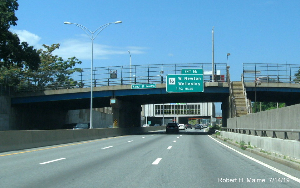 Image of newly placed bridge-mounted 1 1/4 advance overhead sign for MA 16 on I-90/Mass Pike West in Newton