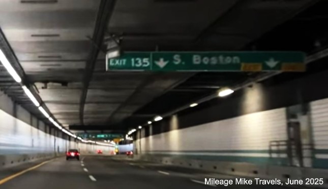 Image of 1/4 Mile advance overhead sign for South Boston exit in Fort Point Channel 
		Tunnel with milepost based exit number on I-90/Mass Pike East in Boston, screen grab from Mileage Mike Travels video, 
		June 2025