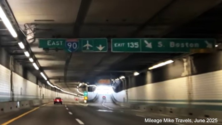 Image of overhead signage at ramp for South Boston exit in Fort Point Channel 
		Tunnel with milepost based exit number on I-90/Mass Pike East in Boston, screen grab from Mileage Mike Travels video, 
		June 2025