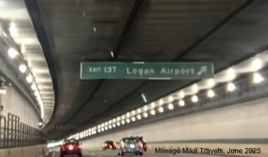 Image of 1/4 mile advance sign for Logan Airport exit connected to ceiling of the 
		Ted Williams Tunnel with milepost based exit number on I-90 East/Massachusetts Turnpike in East Boston, screen grab from 
		Mileage Mile video, June 2025