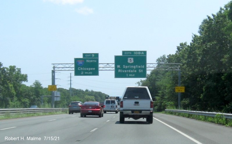 Image of overhead advance signs for I-391 and US 5 exits with new milepost based exit numbers and yellow 
                                         Old Exits 13 A-B and Old Exit 12 advisory sign on right and left supports on I-91 South in West                                          Springfield, July 2021