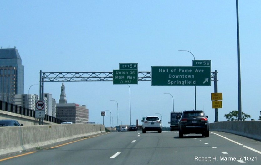 Image of overhead signage at ramp for Hall of Fame Blvd exit with new milepost based exit numbers and yellow Old Exit 6 and 7 signs on right support on I-91 South in Springfield, July 2021