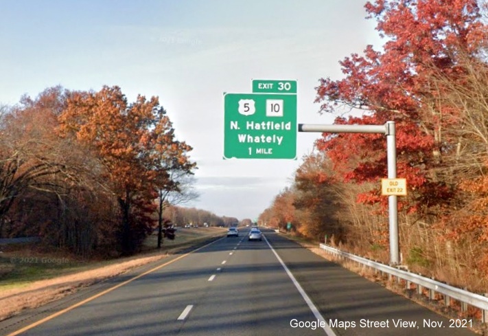 Image of 1 mile advance overhead sign for US 5/MA 10 exit with new milepost based exit number and yellow Old Exit 22 advisory sign on support on I-91 North in Whately, Google Maps Street View image, November 2021