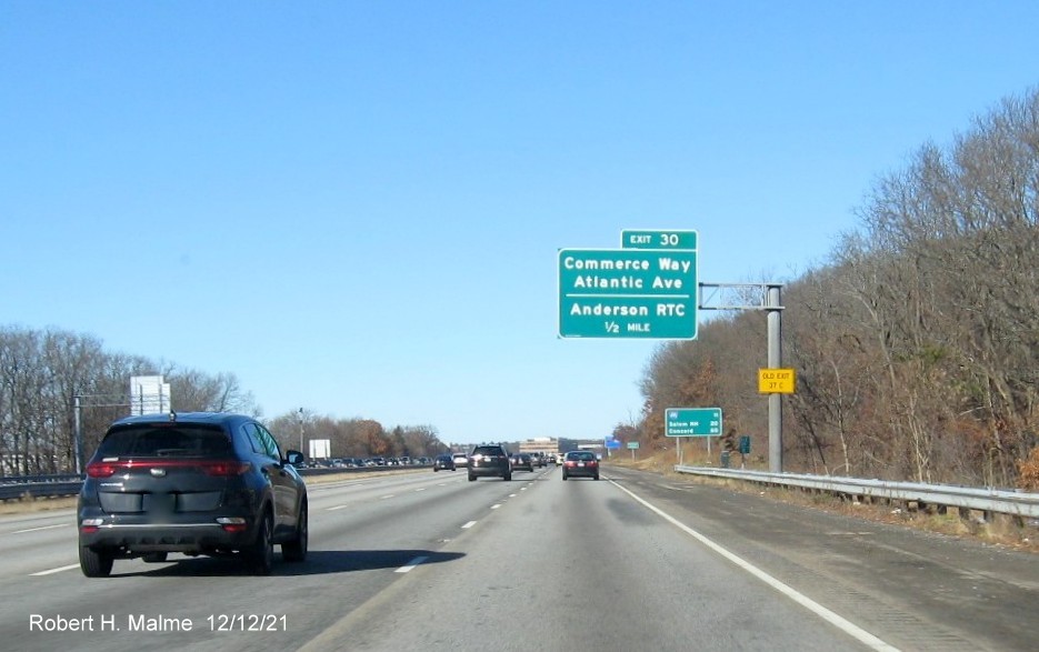 Image of 1/2 mile advance sign for Commerce Way exit with new milepost based exit number and yellow Old Exit 37C advisory sign on support on I-93 North in Woburn, by Paul Schlichtman, May 2021