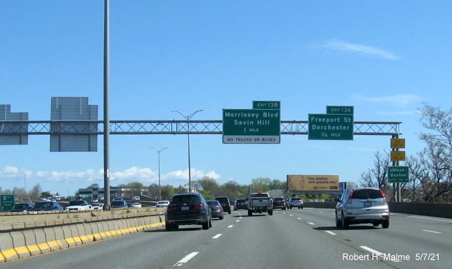 Image of overhead advance signs for Morrissey Blvd and Freeport Street exits with new milepost based exit numbers and yellow Old Exit 13 and 14 advisory signs on right support on I-93/Southeast Expressway North in Dorchester, May 2021