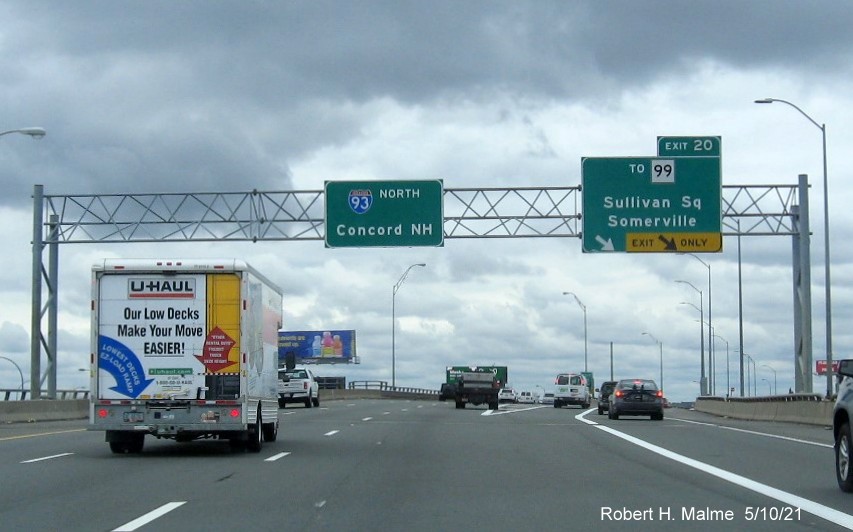 Image of overhead ramp sign for To MA 99 exit with new milepost based 
          exit numbers on I-93 North in Charlestown, May 2021