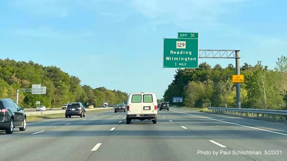 Image of 1 Mile advance sign for MA 129 exit with new milepost based exit number and yellow Old Exit 38 advisory sign on support 
                  on I-93 North in Wilmington, by Paul Schlichtman, May 2021