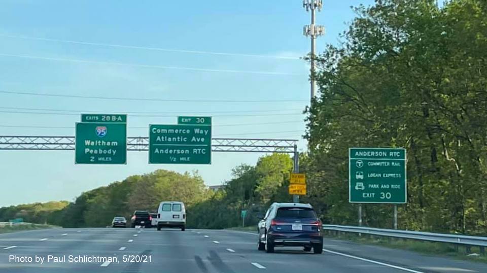 Image of overhead advance signage for I-95/MA 128 and Commerce Way exits with new milepost based exit 
                                            numbers on I-93 South in Woburn, by Paul Schlichtman, May 2021