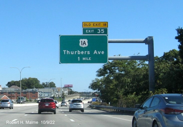 Image of 1 mile advance overhead sign for US 1A exit with new milepost based exit number and yellow Old Exit 18 sign above exit tab, on I-95 North in Providence,  October 2022