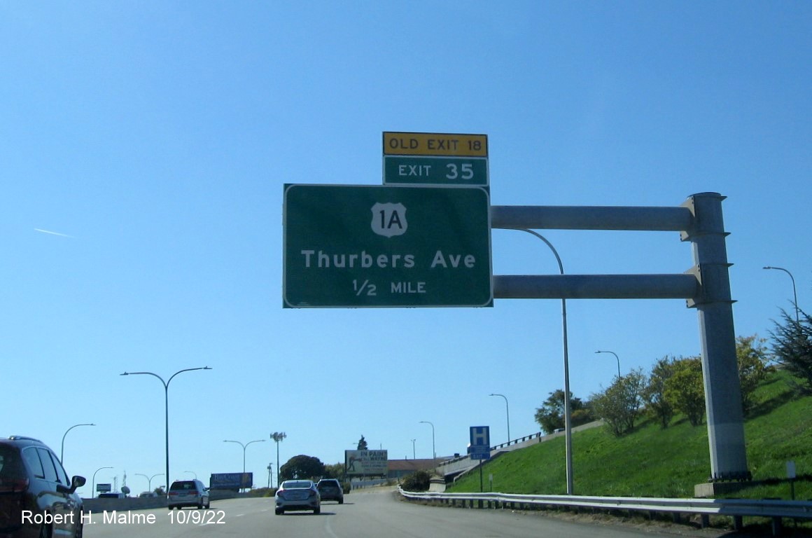 Image of 1/2 mile advance overhead sign for US 1A exit with new milepost based exit number and yellow Old Exit 18 sign above exit tab on I-95 South in Providence, October 2022