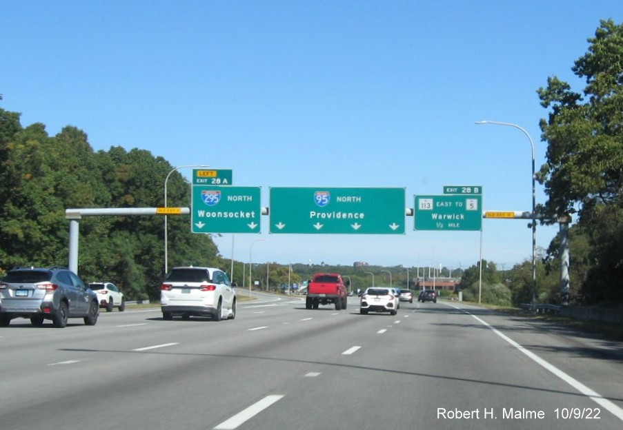 Image of diagrammatic overhead ramp sign for I-295 North exit with new milepost based exit number and yellow Old Exit 11 sign above exit tab on I-95 North in Warwick, October 2022