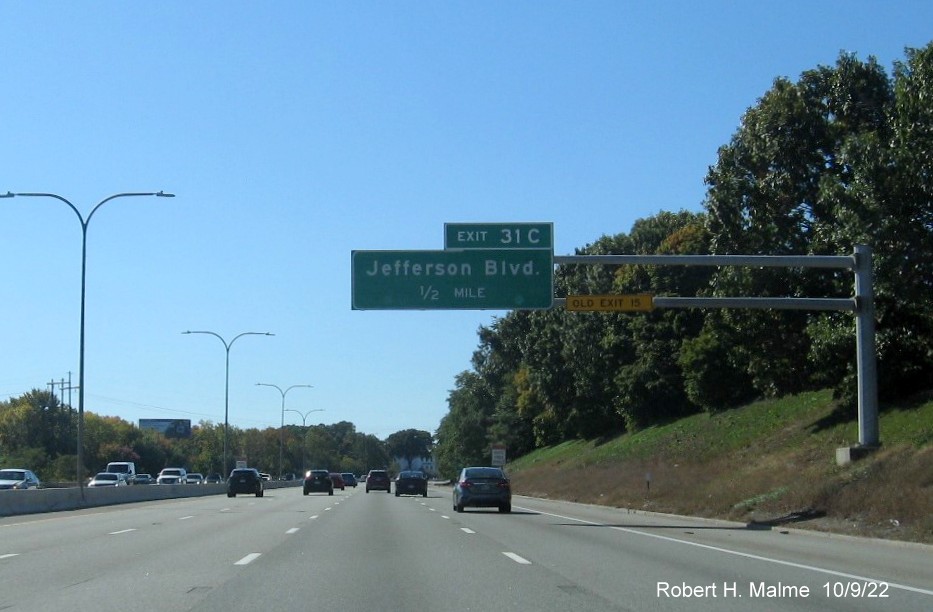 Image of 1/2 mile advance overhead sign for Jefferson Blvd. exit with new milepost based exit number and yellow Old Exit 15 sign on gantry arm on I-95 South in Cranston, October 2022