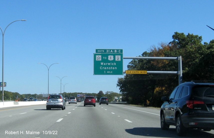 Image of 1 mile advance sign for Jefferson Blvd. and RI 37 exits with new milepost based exit numbers and yellow Old Exits 14-15 sign on gantry arm on I-95 North in Warwick, October 2022