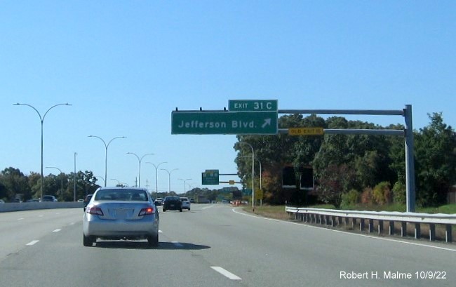 Image of overhead ramp sign for Jefferson Blvd. exit with new milepost based exit number and yellow Old Exit 15 sign on gantry arm on I-95 South in Cranston, October 2022