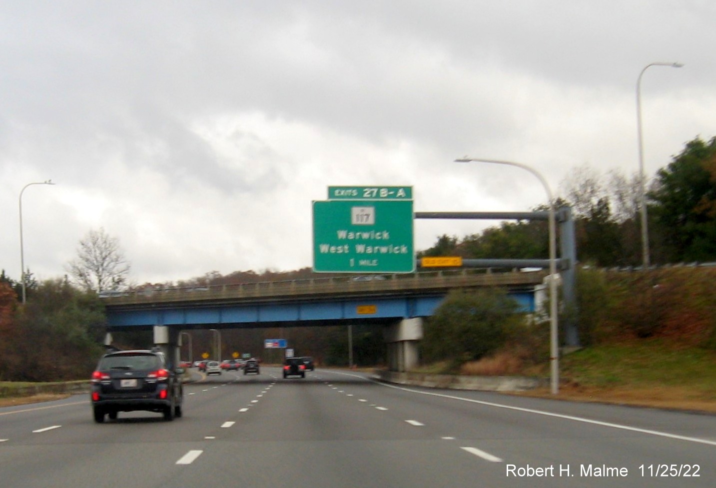 Image of 1 mile advance overhead sign for RI 117 exit with new milepost based exit number and yellow Old Exit 10 advisory sign on gantry arm on I-95 South in Warwick, November 2022