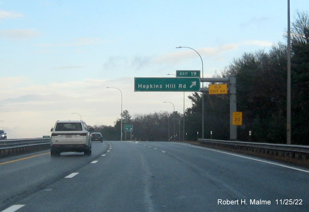 Image of overhead ramp sign for Hopkins Hill Road with new milepost based exit number and yellow Old Exit 6A on top of exit tab on I-95 North in West Greenwich, November 2022