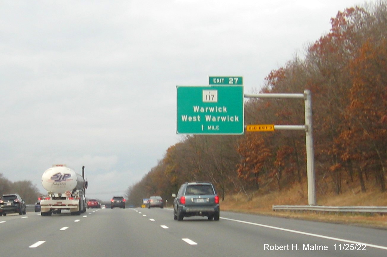 Image of overhead 1 mile advance sign for RI 117 exit with new milepost based exit number and yellow Old Exit 10 sign on gantry arm on I-95 North in West Warwick, November 2022