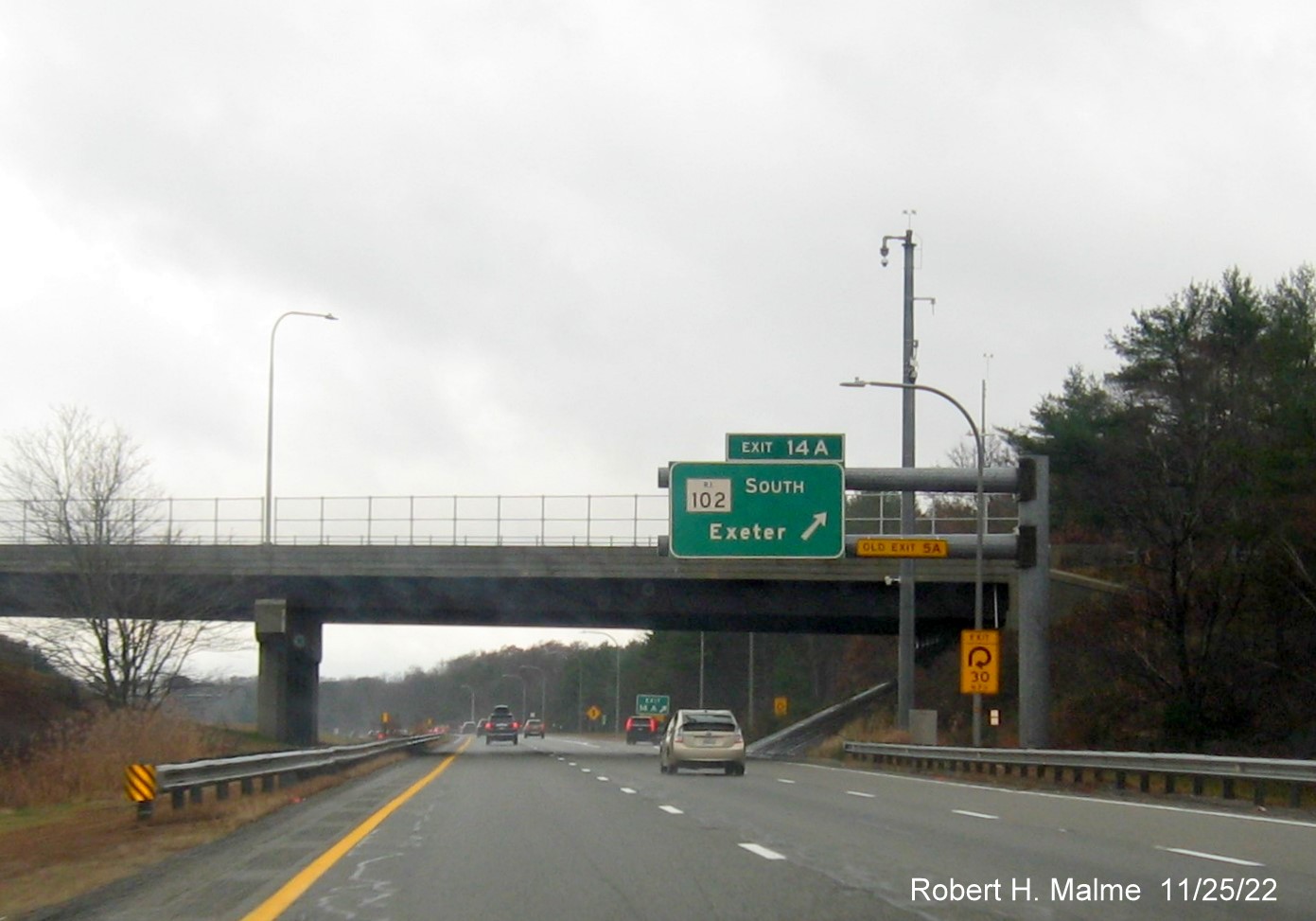 Image of overhead ramp sign for RI 102 South exit with new milepost based exit numbers and yellow Old Exit 5A sign above exit tab on I-95 South in West Greenwich, November 2022
