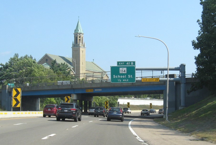 Image of 1/2 mile advance sign for RI 114 exit with new milepost based exit number and yellow Old Exit 28 sign on gantry arm, September 2022