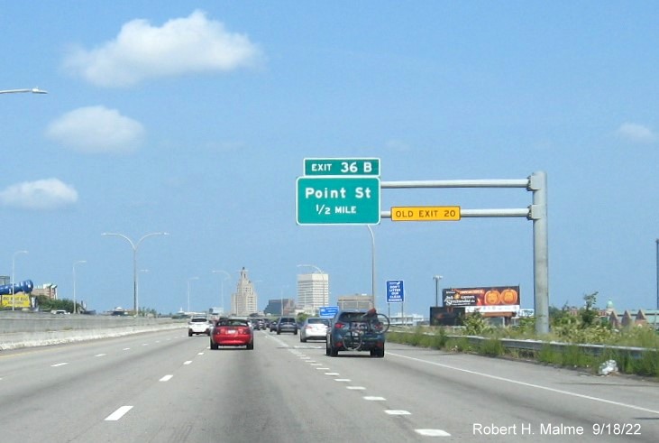 Image of 1/2 mile advance overhead sign for Point Street exit with new milepost based exit number and yellow Old Exit 20 sign on gantry arm on I-95 North in Providence, September 2022