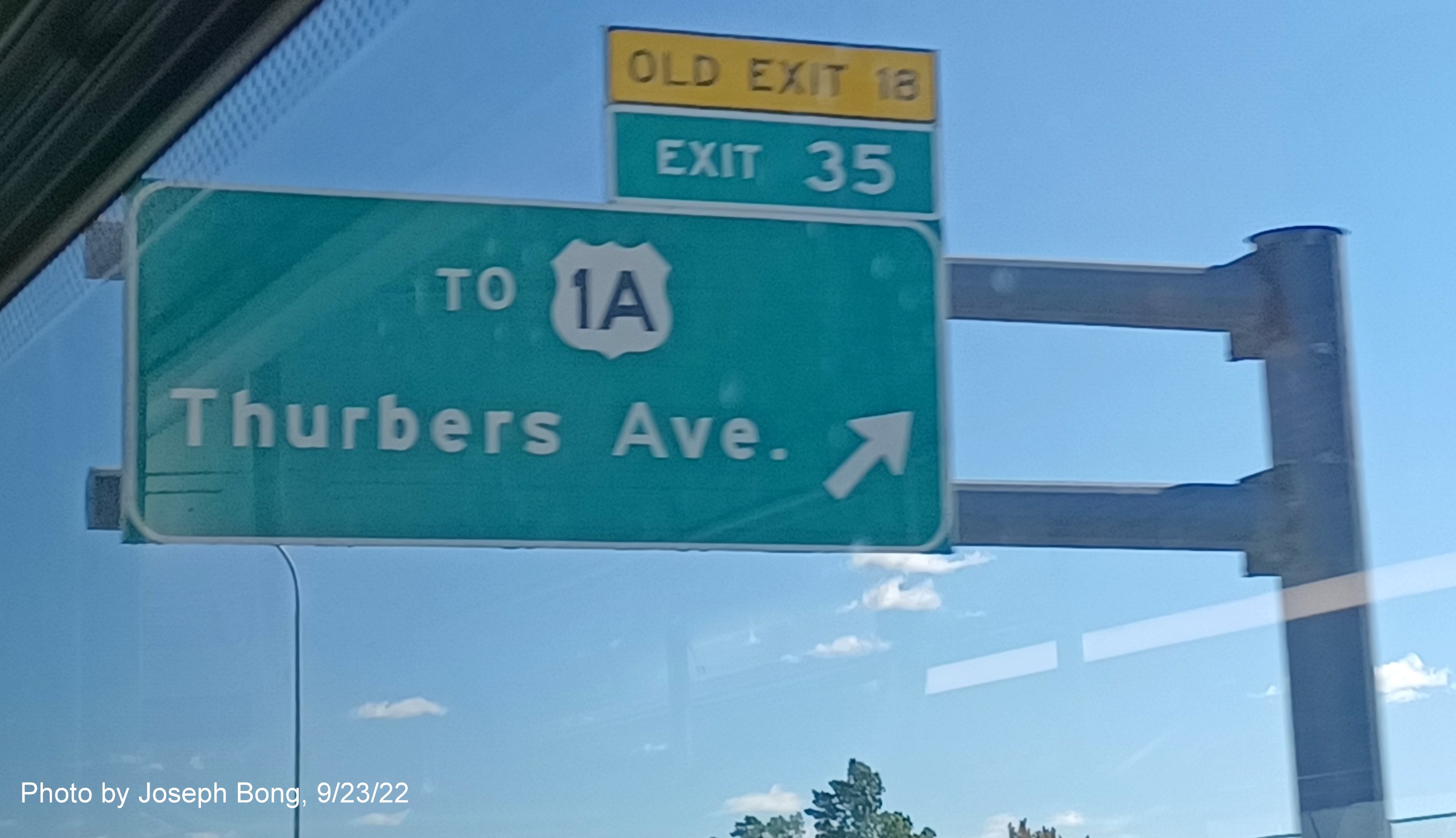 Image of overhead ramp sign for US 1A exit with new milepost based exit number and yellow Old Exit 18 sign above exit tab on I-95 South in Providence, by Joseph Bong, September 2022