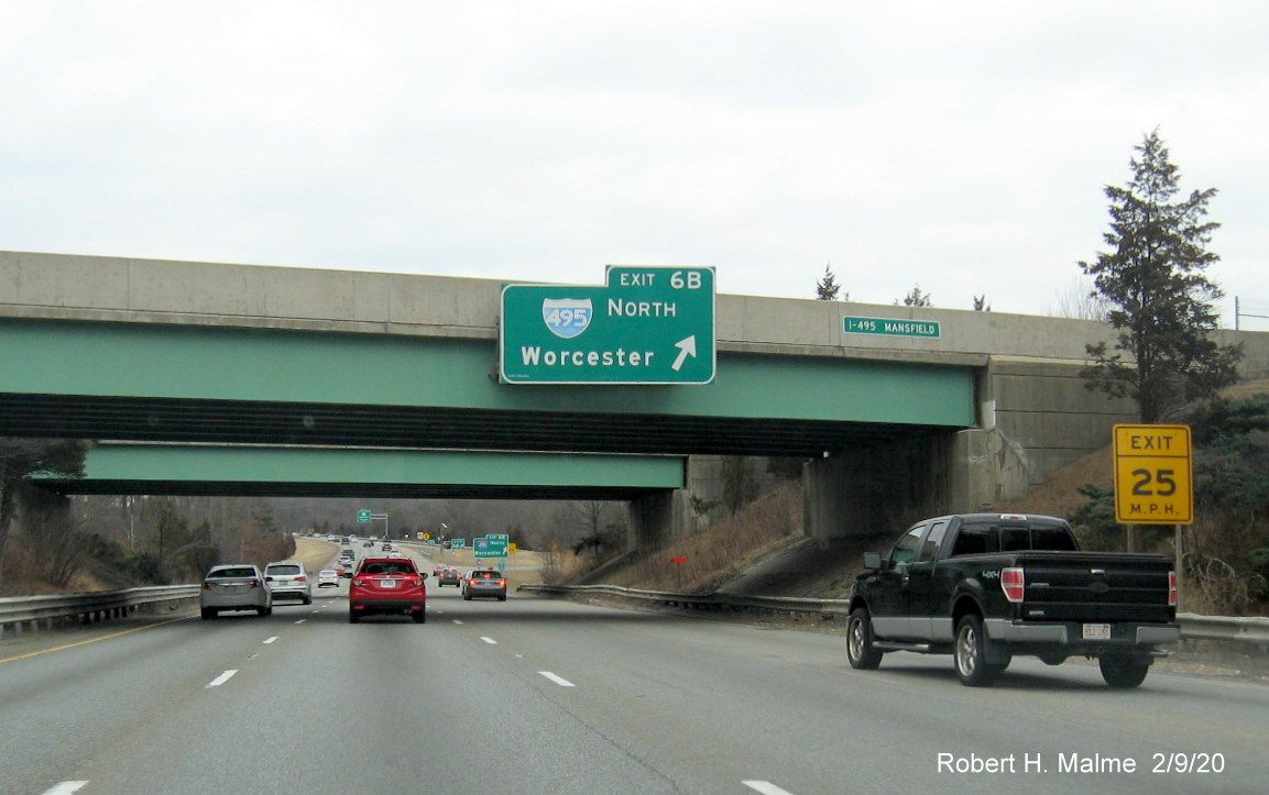 Umage of bridge mounted sign for I-495 South ramp and wide orange contractor tag showing future traffic camera location on I-95 North in Mansfield