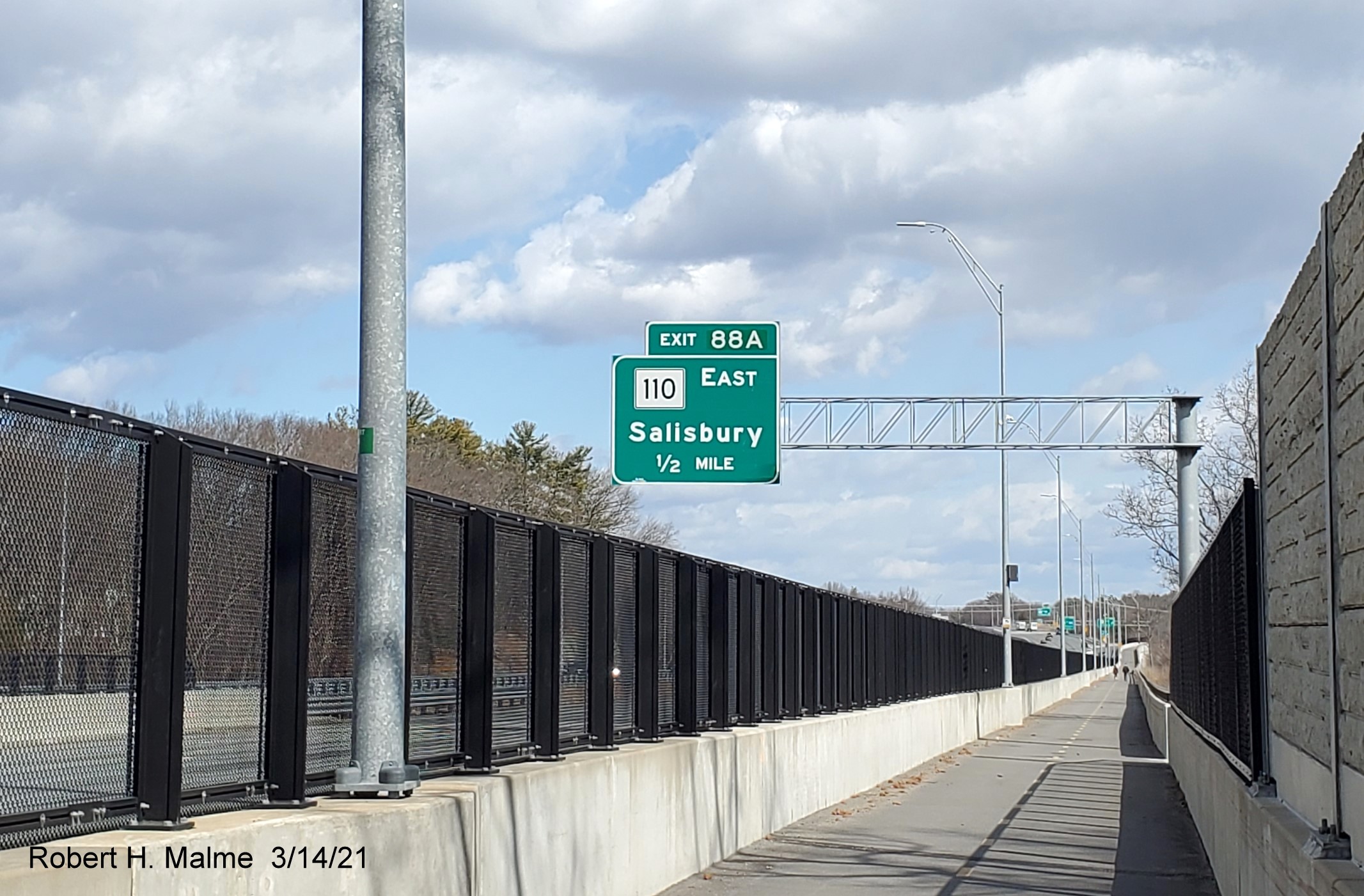 Image of 1/2 mile advance overhead sign for MA 110 exit with new milepost based exit number from Garrison Trail paralleling I-95 North in Amesbury, March 2021
