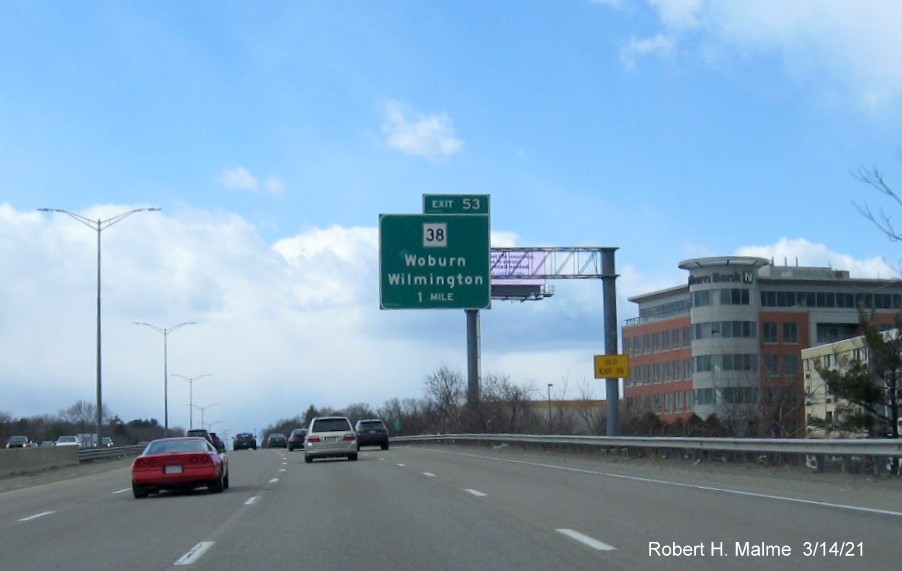 Image of 1-Mile advance overhead sign for MA 38 exit with new milepost based exit number and yellow Old Exit 35 advisory sign on support on I-95/MA 128 South in Woburn, March 2021