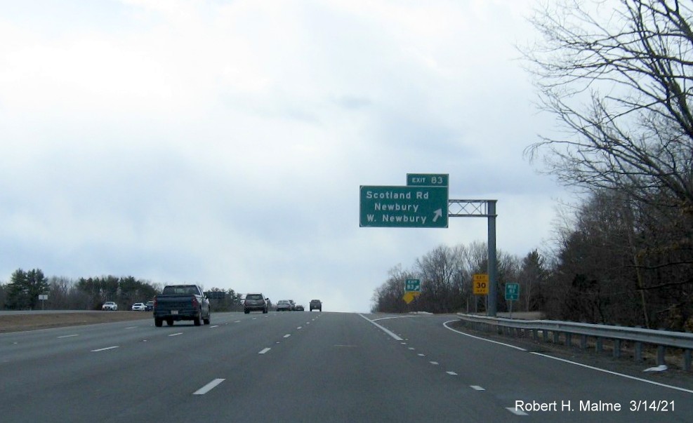 Image of overhead ramp sign for Scotland Road exit with new milepost based exit number and yellow Old Exit 56 sign on support on I-95 South in Newbury, March 2021