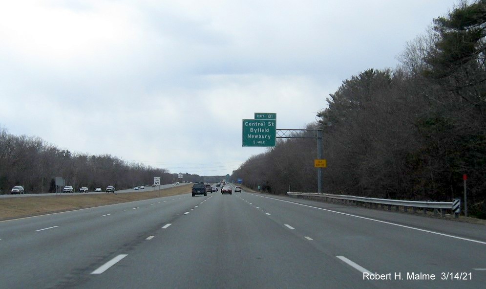 Image of 1-mile advance overhead sign for Central Street exit with new milepost based exit number and yellow Old Exit 55 sign on support on I-95 South in Newbury, March 2021