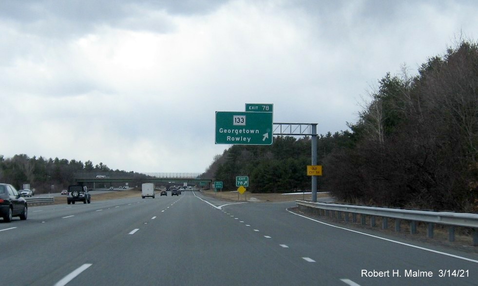 Image of 1 mile advance overhead sign for MA 133 exit with new milepost based exit number and yellow Old Exit 54 advisory sign on support on I-95 South in Georgetown, March 2021 