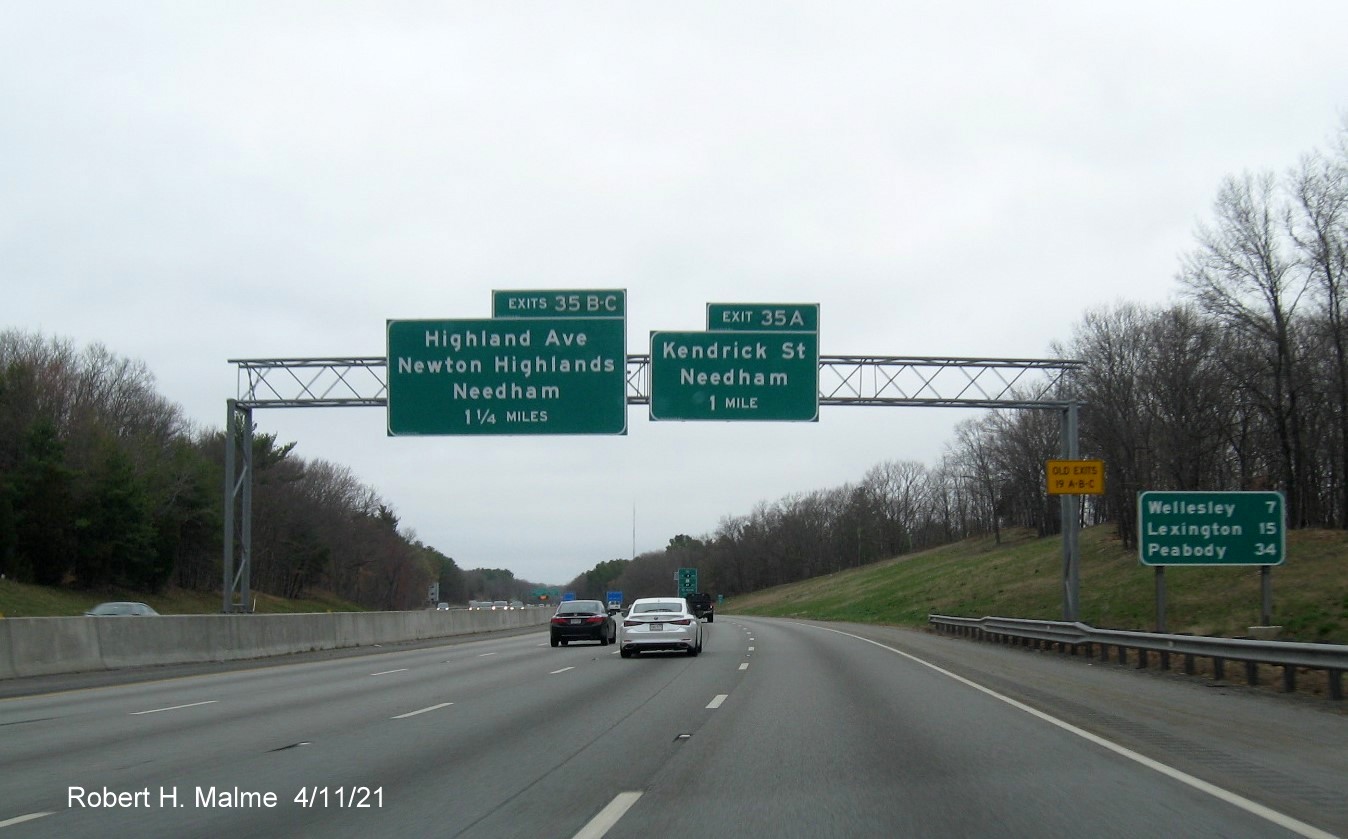 Image of 1 and 1 1/2 Mile advance signs for Kendrick Street and Highland Avenue exits with new milepost 
                                            based exit numbers and yellow Old Exits 19 A-C advisory sign on right support on I-95/MA 128 North in Needham, April 2021