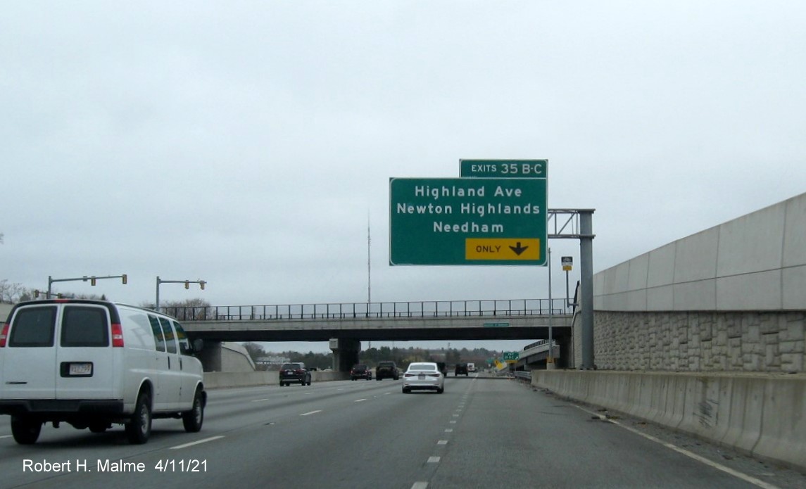 Image of overhead ramp exit only sign for Highland Avenue exits with new milepost 
                                            based exit numbers on I-95/MA 128 North in Needham, April 2021